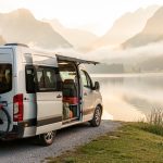 Équipements vélo camping-car : les 8 indispensables à prévoir Camping-car stationné au bord d’un lac avec des vélos chargés et du matériel de voyage soigneusement rangé dans la lumière douce du matin.